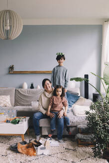 Portrait of happy family collecting waste in living room at home - MASF39361