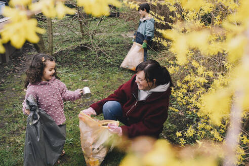 Glückliche Tochter hilft Mutter beim Müllsammeln im Hinterhof - MASF39366