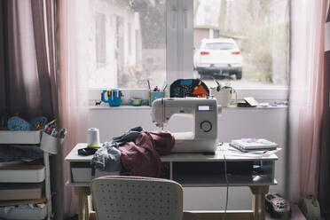 Nähmaschine mit Kleidung auf dem Tisch zu Hause - MASF39369