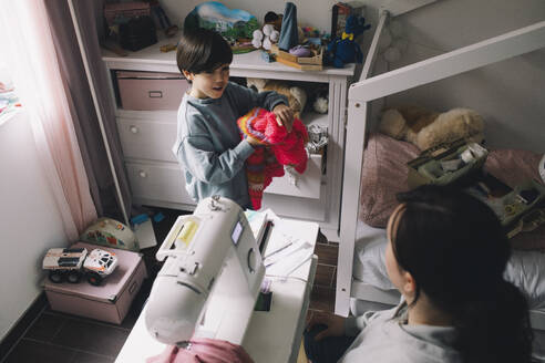 Hochformatiger Blick auf einen Jungen mit warmer Kleidung, der sich mit seiner Mutter zu Hause unterhält - MASF39372