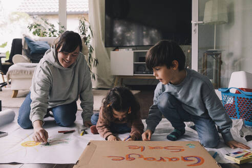 Mutter zeichnet mit Sohn und Tochter im Wohnzimmer zu Hause - MASF39378