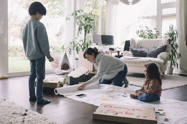 Mother with son and daughter drawing on textile in living room at home - MASF39379