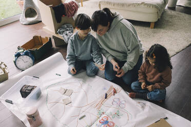 Mutter mit Sohn und Tochter zeichnen Baum auf Tuch im Wohnzimmer zu Hause - MASF39380