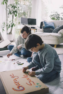 Mutter und Sohn zeichnen im Wohnzimmer zu Hause - MASF39388