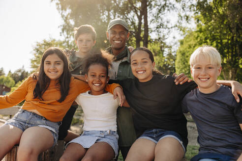 Portrait of male camp counselor with happy kids at summer camp - MASF39403