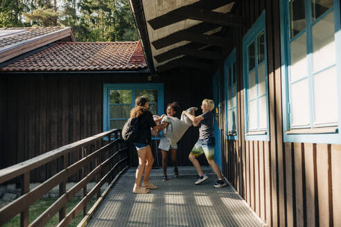 Fröhliche Kinder spielen mit Kissen im Korridor neben der Hütte im Ferienlager - MASF39444