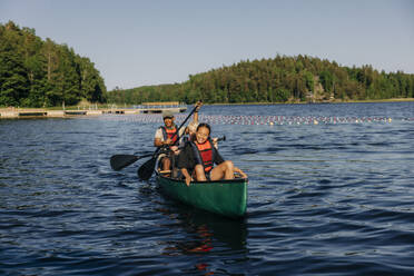 Lächelndes Mädchen beim Kajakfahren mit Betreuer auf einem See im Sommercamp - MASF39455