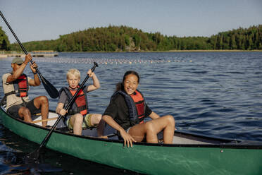 Kids enjoying while doing kayaking with counselors on lake at summer camp - MASF39456