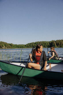 Mädchen schaut weg, während sie im Kajak auf dem See im Sommerlager sitzt - MASF39460
