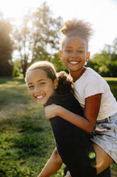 Portrait of happy girl piggybacking female friend at summer camp - MASF39468