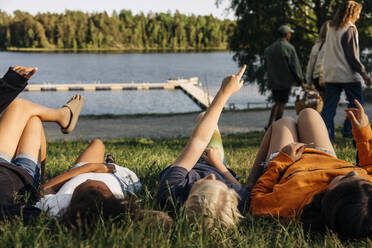 Junge zeigt auf einen Punkt, während er mit Freunden im Sommerlager im Gras liegt - MASF39471