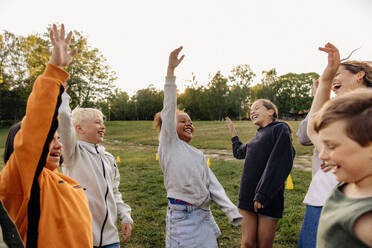 Carefree kids dancing with hand raised in playground at summer camp - MASF39517