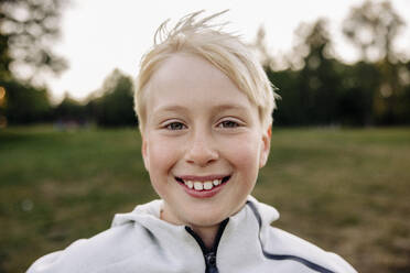 Porträt eines lächelnden blonden Jungen auf dem Spielplatz - MASF39549