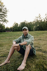 Portrait of man sitting on grass in playground - MASF39555