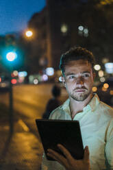 Young businessman with tablet PC on street at dusk - JOSEF20966