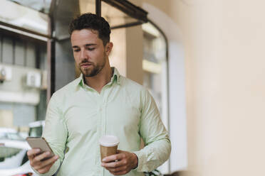 Young businessman using smart phone in cafe - JOSEF21004