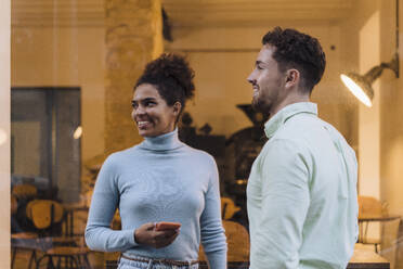 Happy businesswoman standing with colleague outside cafe - JOSEF21011