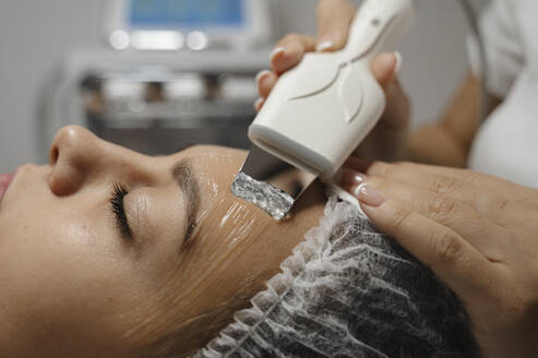 Dermatologe führt Ultraschall-Gesichtsreinigung auf dem Gesicht einer Frau durch - ALKF00614