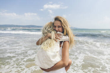 Glückliche Mutter, die ihre Tochter am Strand umarmt - SIF00866