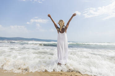 Woman standing with arms outstretched in water at beach - SIF00873