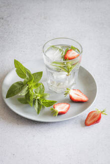 Studioaufnahme eines Glases Mineralwasser mit Minze und Erdbeeren - EVGF04377