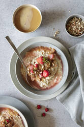 Studioaufnahme einer Schüssel mit veganem Porridge mit Erdbeeren und Mandeln und Rhabarberkompott - EVGF04385