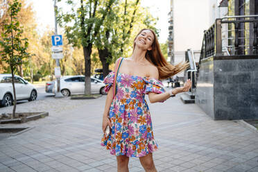 Happy woman with long hair standing at footpath - NLAF00096