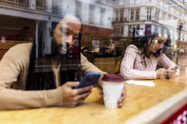 Mann und Frau benutzen ein Smartphone in einem Cafe - WPEF07677