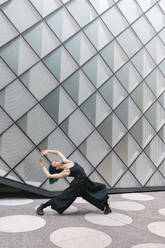 Young dancer bending over backwards in front of modern building - MMPF00870
