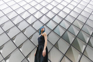 Young woman with dyed hair standing in front of patterned wall - MMPF00887