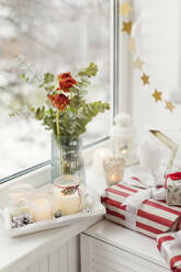 Weihnachtsgeschenke und Kerzen mit roten Tulpen am Fenster - ONAF00636