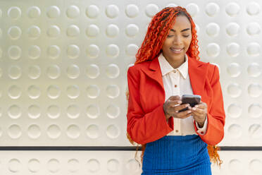 Smiling businesswoman using smart phone in office - DLTSF03612
