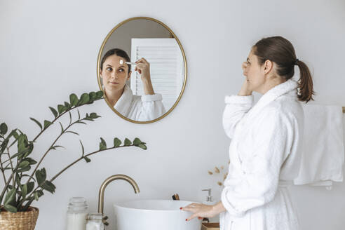 Frau macht Hautpflege-Routine im Badezimmer - EVKF00068