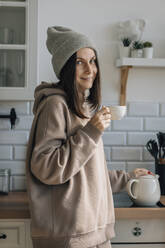 Lächelnde Frau mit Teetasse in der Küche - EVKF00082