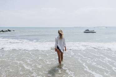 Frau geht am Strand im Wasser spazieren - SIF00882