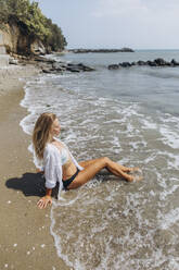 Frau mit geschlossenen Augen entspannt sich am Meer am Strand - SIF00885