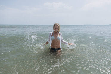 Smiling woman splashing water in sea - SIF00889