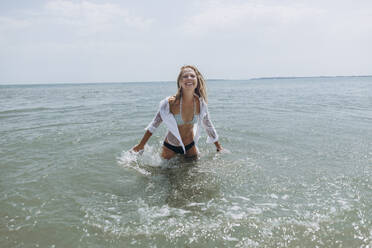 Happy playful woman splashing water in sea - SIF00894