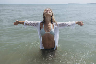 Happy woman with arms outstretched standing in sea - SIF00896