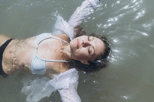Frau mit geschlossenen Augen schwimmt auf dem Wasser - SIF00898