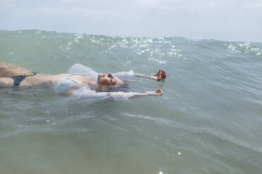Frau im Bikini schwimmt auf dem Wasser im Meer - SIF00899