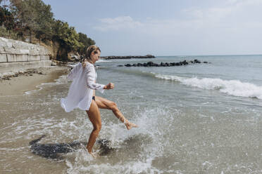 Woman splashing water with leg at beach - SIF00901