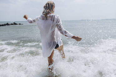 Carefree woman splashing water at beach - SIF00905