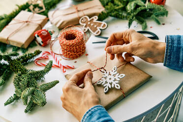 Von oben der Ernte anonyme Person binden Band auf Geschenk auf dem Tisch in der Nähe von verschiedenen Geschenk-Boxen für Weihnachten dekoriert platziert - ADSF46719