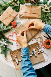 Frau bereitet Weihnachtsgeschenke mit Seil und Weihnachtsschmuck vor - ADSF46728