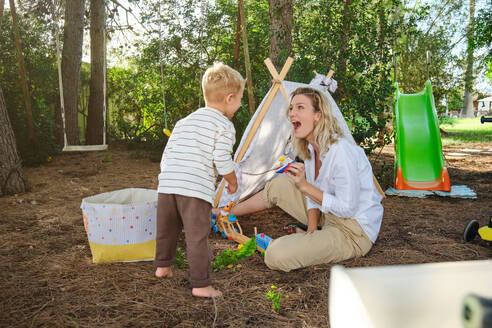 Vollkörper der überraschten Mutter, die mit ihrem Sohn spielt, während sie gemeinsam Zeit im Park verbringen - ADSF46772
