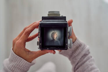 Crop unerkennbare Person zeigt Fotografie von Kind auf Vintage-Kamera-Bildschirm auf hellem Hintergrund - ADSF46793
