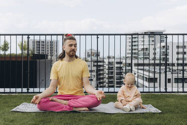 Vater beim Yoga und mit Blick auf die Tochter auf der Dachterrasse - AGRF00005