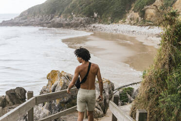 Mann ohne Hemd geht in der Nähe des Geländers am Strand - PBTF00245