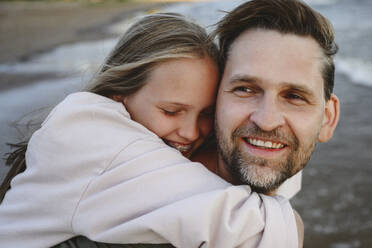 Happy daughter hugging father at beach - EYAF02821